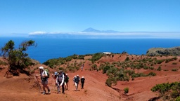 Grupo de senderismo caminando sobre las tierras rojas en Abrante y vistas del Teide